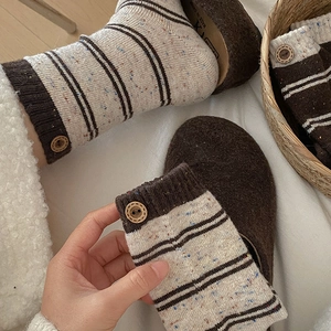 Close-up of retro wool socks featuring speckled yarn, striped pattern, and decorative button