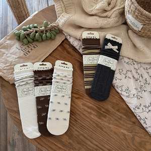 Detailed set of floral knit socks with lace edges and bows on a rustic wooden background