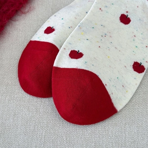Détail rapproché de chaussettes en tricot crème avec pointe rouge et motif de pomme