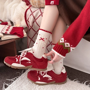 Detail of red polka dot knit socks with bow and retro sneakers in warm festive setting