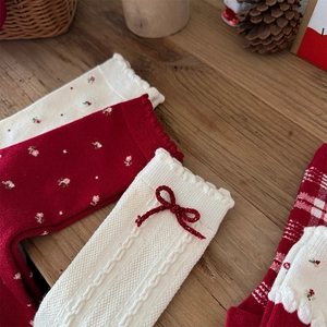 Close-up of vintage floral knit wool socks with red ribbons and plaid pattern details