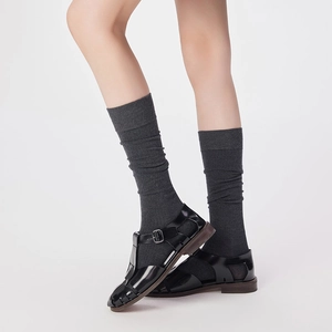 Detail of dark grey knit calf socks paired with black Mary Jane T-strap leather shoes
