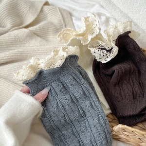 Close-up of ribbed knit leg warmers with white lace trim in grey and dark brown colors