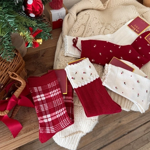 Detail of red festive socks with floral and plaid patterns on beige knit fabric