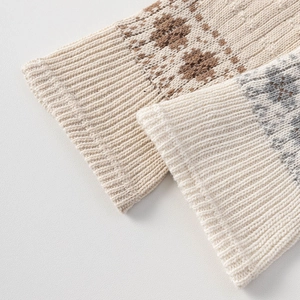 Detailed view of cream knitted leg warmers with brown jacquard and ribbed cuff texture
