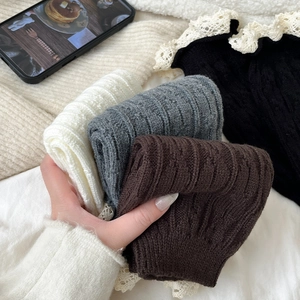 Detail of knitted leg warmers with delicate white lace trim in multiple colors