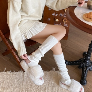Dettaglio di scaldamuscoli in maglia bianco crema con morbide pantofole in pelliccia