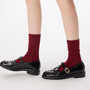 Detail of black Mary Jane shoes with woven texture and burgundy socks on a model
