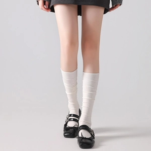 Detailed texture of white ribbed wool knee-high socks styled with Mary Jane shoes