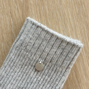 Close-up of gray wool ribbed knit fabric with decorative silver metal button detail