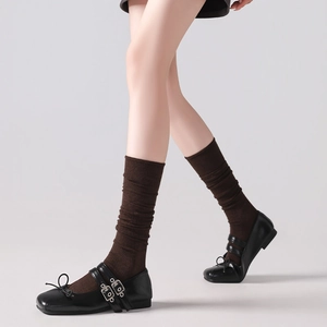 Detail of dark brown ribbed wool socks paired with black Mary Jane buckle shoes
