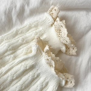 Detailed macro view of cable knit leg warmer with delicate crochet lace trimming