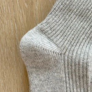 Detailed macro view of gray knitted wool socks with reinforced heel and rib texture