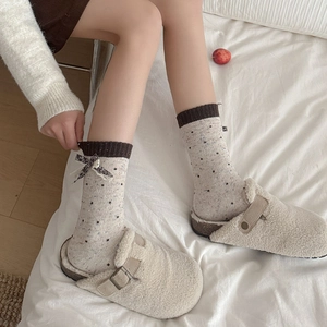 Polka dot wool socks with bow and plush mule slippers in a cozy home setting