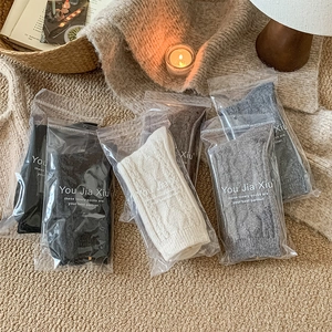 Detailed view of four pairs of thick knit wool socks in neutral tones with cable textures