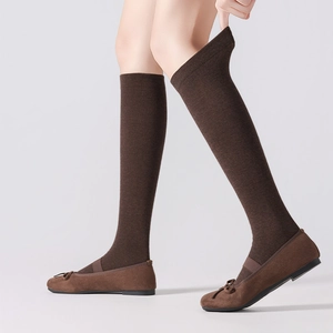 Detail of dark brown knitted calf socks with elastic cuffs paired with bow flat shoes