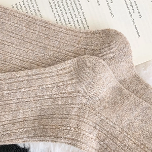 Macro detail of thick oatmeal rib-knit wool socks featuring vertical texture and reinforced heel
