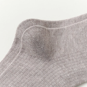 Macro view of purple rib-knit wool socks showing heel reinforcement and fabric texture