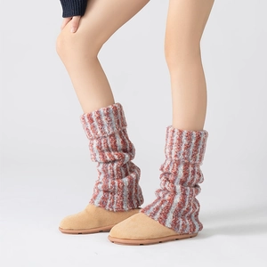 Détail des jambières tricotées à rayures rouges et grises sur des bottes en daim beige