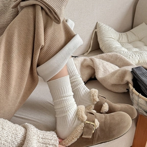 Close-up of brown suede slippers with wool lining paired with white striped crew socks