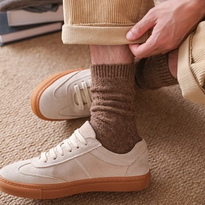 Detail of dark brown cable knit wool socks paired with corduroy trousers and sneakers