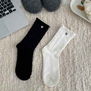 Detail of ruffled cuffs and metal buckle on ribbed knit socks over a plush rug