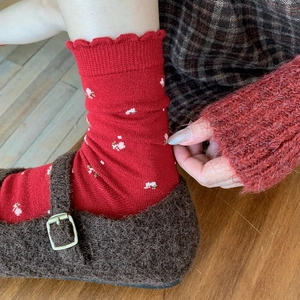 Detail of vintage red floral wool socks with ruffle cuffs and brown Mary Jane shoes