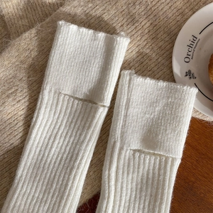Primo piano di scaldamuscoli in maglia bianca con coste verticali su sfondo accogliente