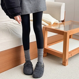 Detail of gray knitted slouch socks paired with dark wool felt mules and black leggings