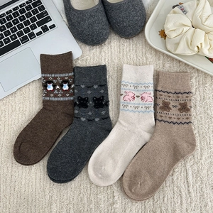 Flat lay of four pairs of warm knitted animal socks on a cozy cream textured rug