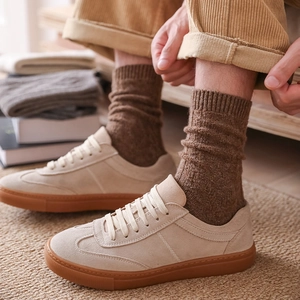 Close-up of beige suede casual sneakers with thick wool socks and corduroy trousers