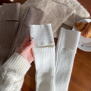 Dettaglio di scaldamuscoli in maglia a costine in bianco, marrone e cammello per l'autunno