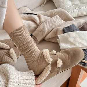 Close-up of khaki ribbed slouch socks paired with fluffy shearling-lined boots for winter
