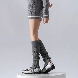 Close-up of dark grey ribbed knit leg warmers with vertical stripes and layered texture