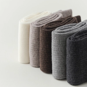 Detailed view of five pairs of wool socks in various earth tones with vertical ribbed knit