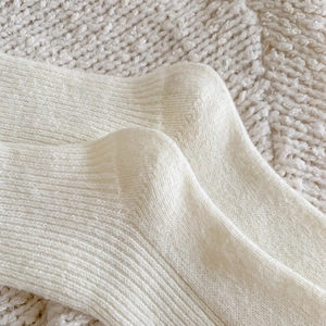 Macro detail of cream knit socks showing ribbed texture and warm wool blend fabric