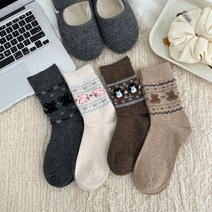 Close-up of four pairs of warm winter socks with cute animal embroidery on a cozy rug
