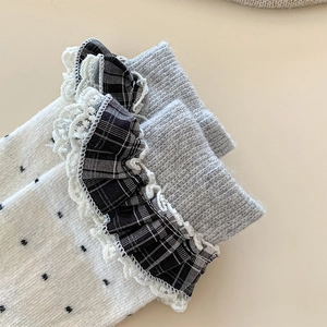 Detail of white cotton socks with black polka dots and delicate lace trim cuff