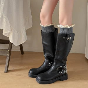 Lace trim knitted leg warmers with black leather biker boots in a cozy indoor setting