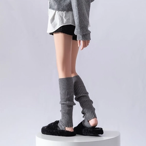 Detail of grey ribbed knit leg warmers paired with black plush open-toe slippers