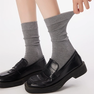 Detailed knit ribbing and elastic stretch of gray mid-calf wool socks with leather shoes