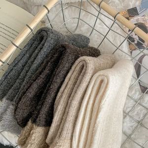 Close-up of thick rib-knit wool socks in earthy tones displayed in a wire basket