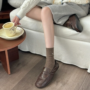 Close-up of brown leather loafers with ribbed knit socks in a cozy home setting