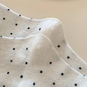 Close-up of knit wool socks with black polka dots and delicate lace trim details