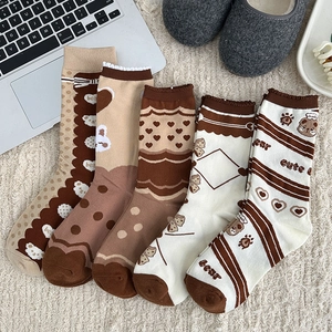 Vue détaillée de cinq paires de chaussettes d'ours marron sur un tapis blanc doux