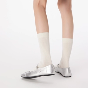Close-up of silver Mary Jane flats with white knit socks and delicate buckle strap