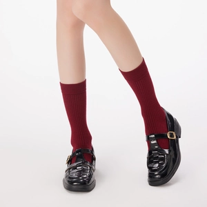 Detail of dark red ribbed wool socks paired with black patent leather Mary Jane shoes