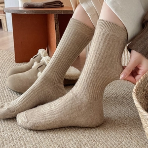 Close-up of thick beige ribbed knit socks showing high elasticity and soft wool texture