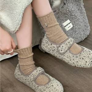 Detail of warm teddy plush Mary Jane house shoes with soft beige ribbed wool socks