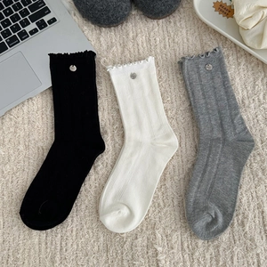 Detail of ruffle cuff crew socks in black, white and grey with metal buckle accents